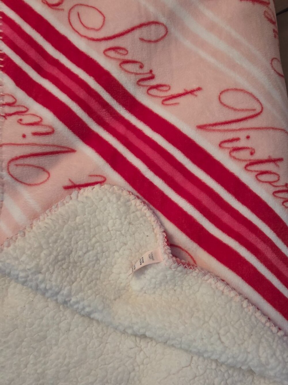 Victoria's Secret Cozy Plush Blanket features cozy white sherpa fleece on the re